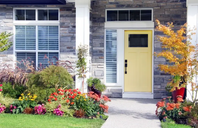 Front door of a home and walkway with annual and perennial plants. 