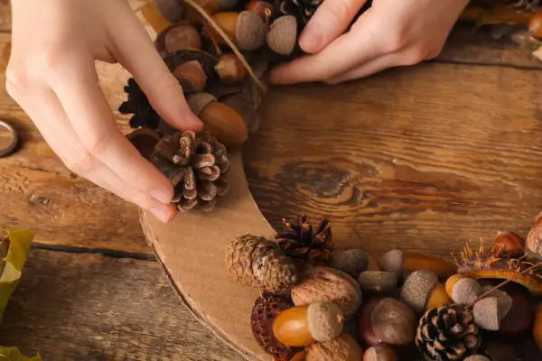 Person making holiday craft with acorns.