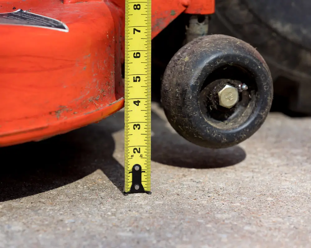 Landscaper measuring blade height on lawn mower