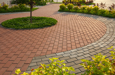 Brick paver path surrounded by neat mulch and flower beds.
