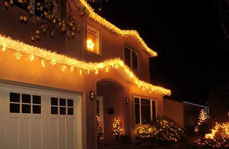 Single-family home at night lit with holiday lights.