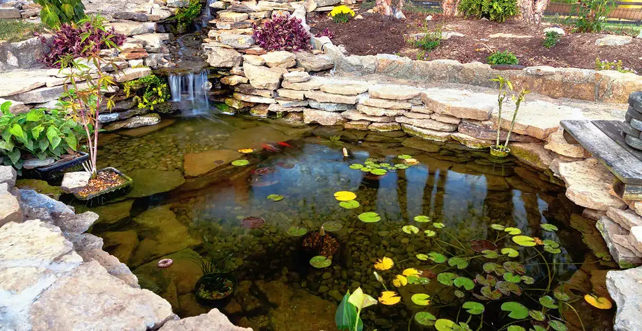 A decorative koi pond in a home's backyard.
