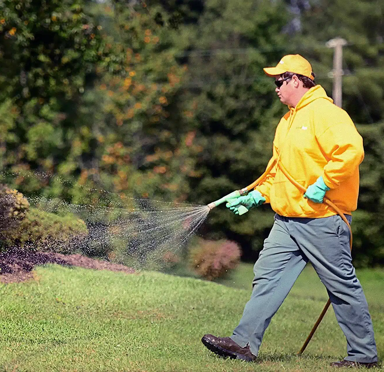 The Grounds Guys service professional spraying a lawn with pesticide.