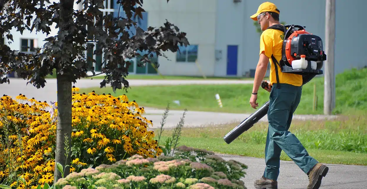 The Grounds Guys service professional using a leaf blower to clean up after a storm.