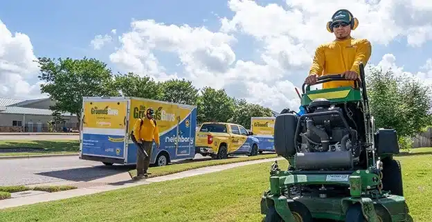 The Grounds Guys team mowing and edging a commercial property's lawn.
