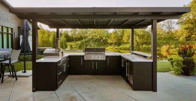 An outdoor kitchen on a backyard patio, built in a U-shape design with a powder-coated galvanized steel roof.