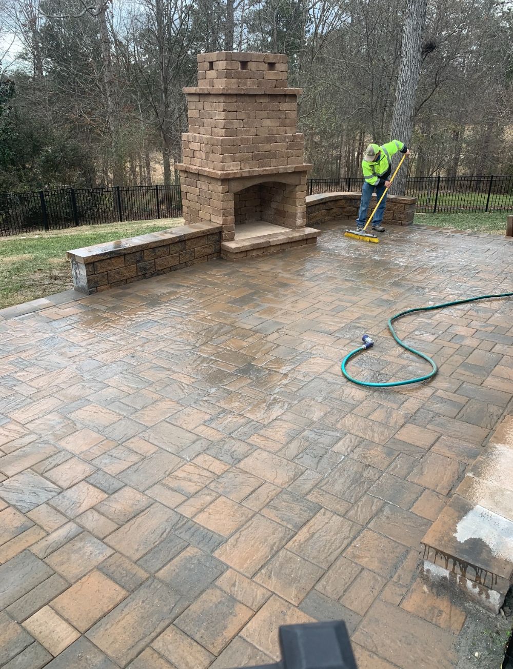 Large paver patio in lovely basketweave pattern. Tall matching stone fireplace and sitting wall area in the backyard.