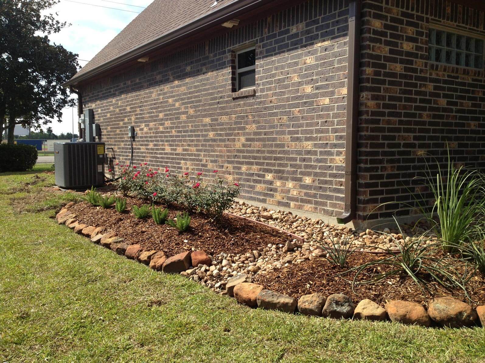 Soil and stone landscape on side of brick house