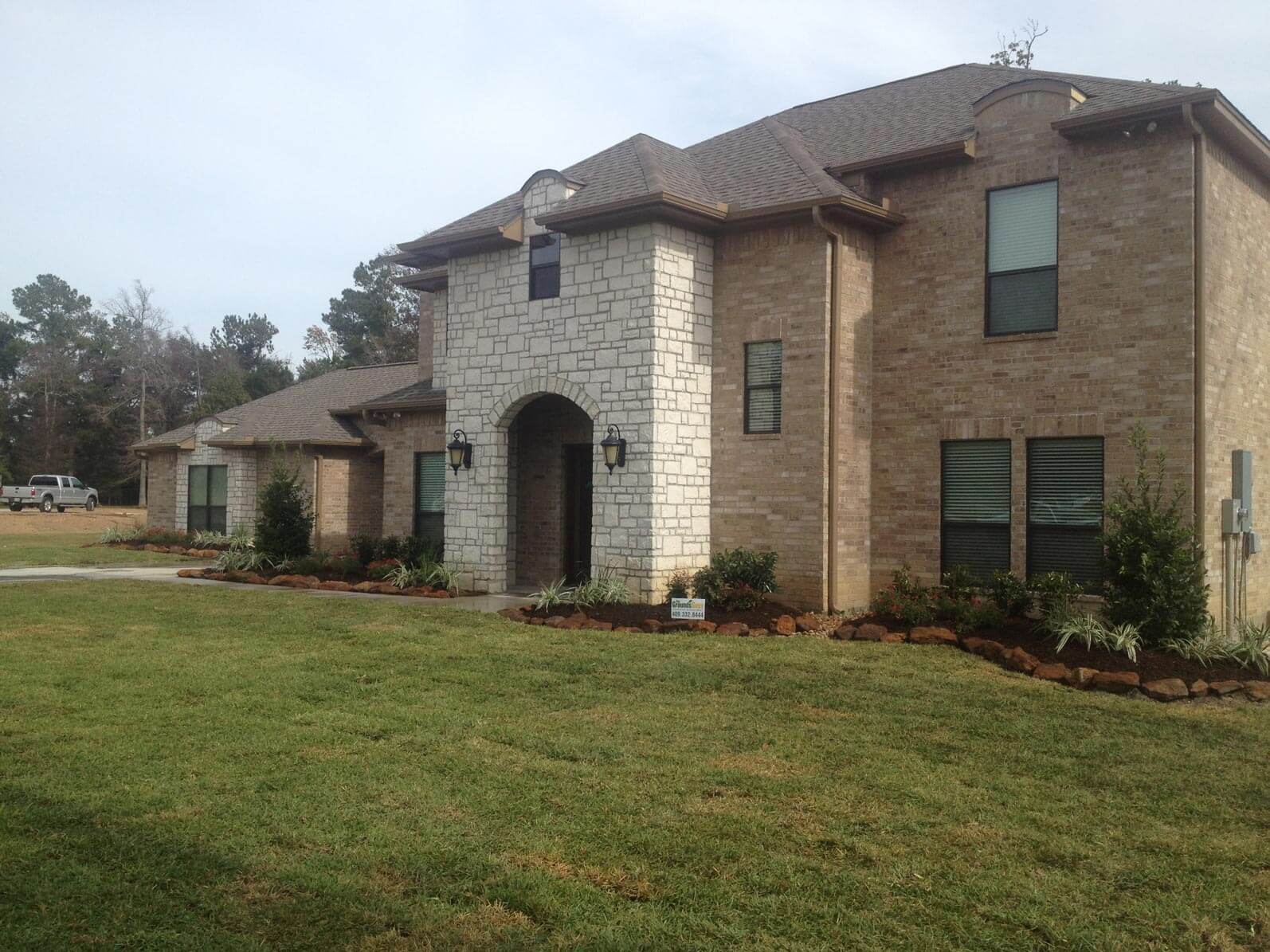 stone house lined wiht bush and tree landscaping