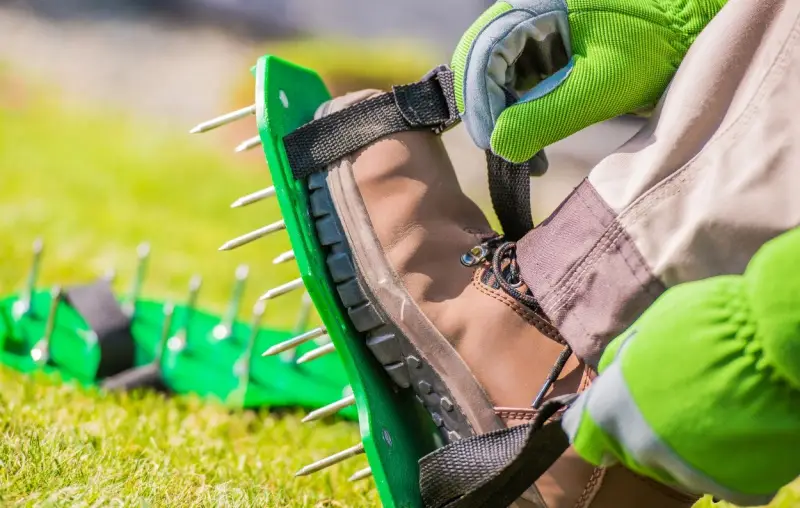 Landscaper putting on spike shoes for lawn aeration.