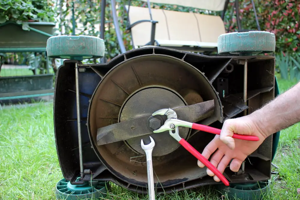 Landscaper performing maintenance on lawn mower