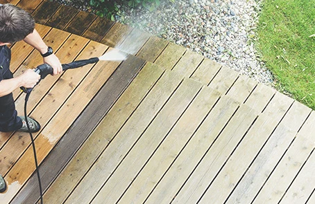 A service professional power washing a deck.