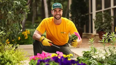 A Grounds Guys service professional planting seasonal flowers as part of a year-round landscape color plan.