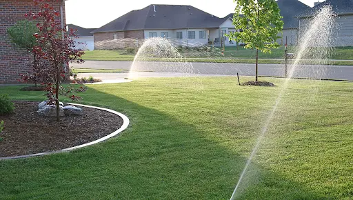 A residential irrigation system watering a home's front lawn during a sprinkler performance evaluation.