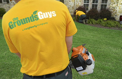 A Grounds Guys landscaper performing seasonal yard clean up