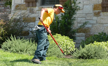 Grounds Guys landscaper performing lawn maintenance.
