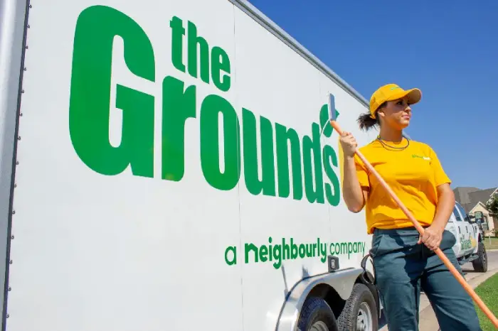 Grounds Guys lawn expert standing next to a trailer
