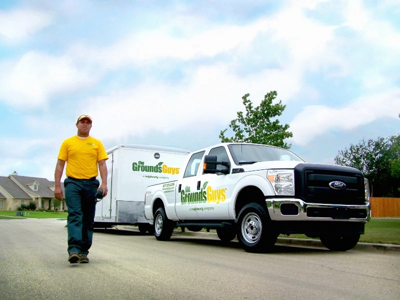 Grounds Guys lawn expert walking in front of his truck.
