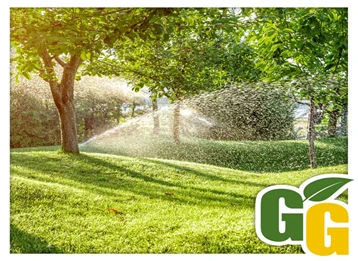 Water spraying green lawn and trees from embedded irrigation system.