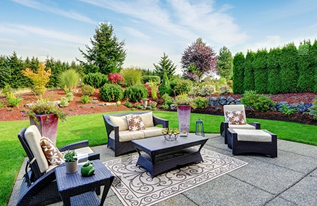 A lush backyard landscape and patio hardscape with outdoor furniture