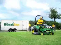 Grounds Guys lawn expert mowing a lawn.