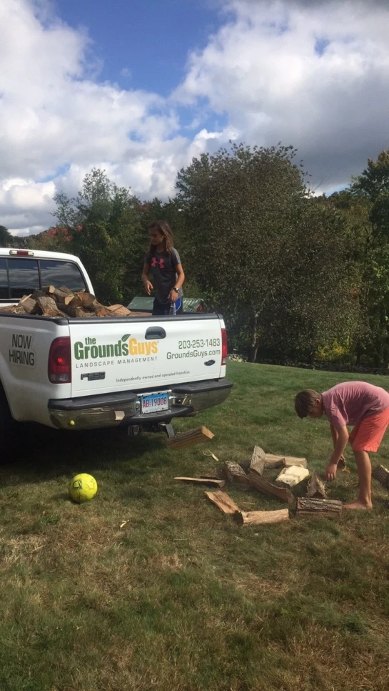 Children loading the Grounds Guys truck with wood